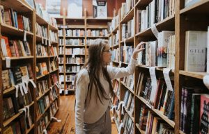 Endless Research needs a guide. Image by https://unsplash.com/photos/woman-holding-book-on-bookshelves-GnY_mW1Q6Xc